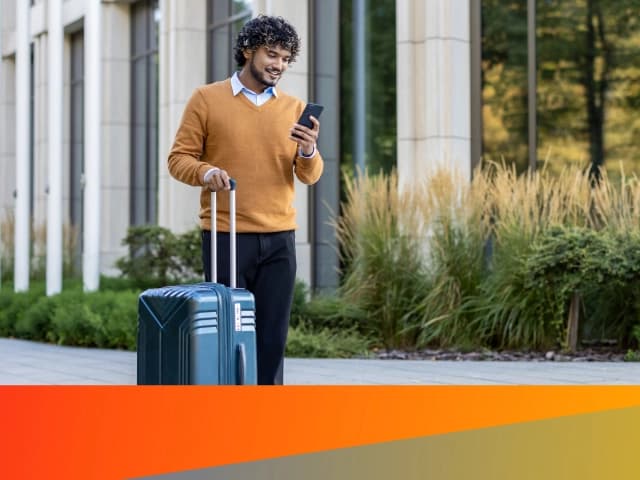 Man with suitcase holding a phone